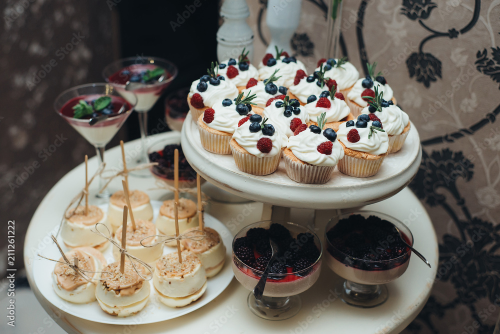 Sweet table. A plates of cakes and muffins with cream with berries