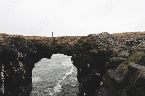 Iceland, Arnarstapi, woman standing on rock arch photo