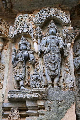 Ornate wall panel reliefs depicting from left Goddess Lakshmi the wife of Vishnu, and Vishnu, Kedareshwara temple, Halebidu, Karnataka