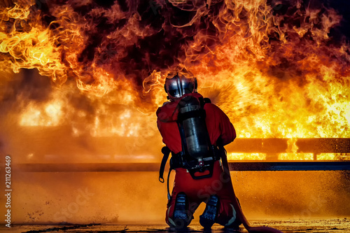 Firefighter training., fireman using water and extinguisher to fighting with fire flame in an emergency situation., under danger situation firemen wearing fire fighter suit for safety. © sanchairat