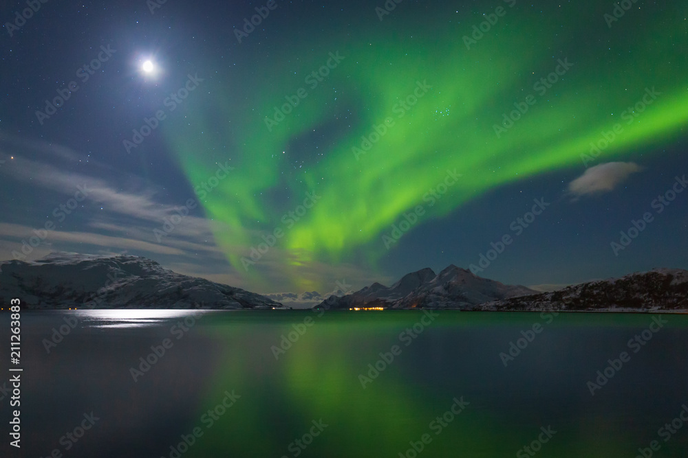 Intense green northern lights over mountains and fjord