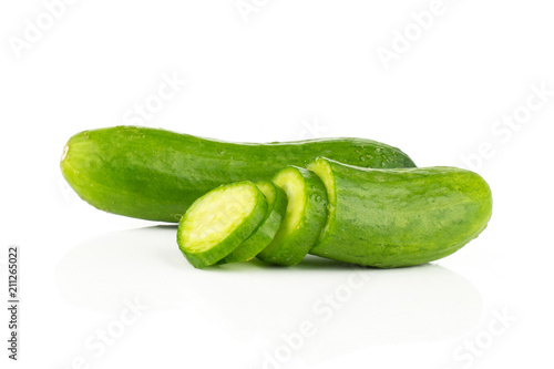 One fresh green mini cucumber with a sliced half and three slices isolated on white background.