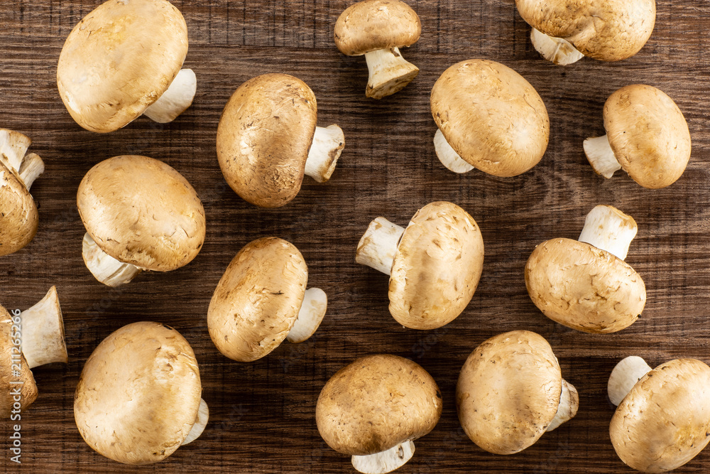 Fresh brown champignons top view on brown wood background raw mushrooms. Fresh brown champignons top view on brown wood background raw mushrooms.