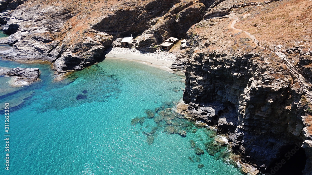 Aerial drone bird's eye view of iconic beach of Grias Pidima with giant rock rare geological formation and turquoise crystal clear waters, near village of Korthi, Andros island, Cyclades, Greece