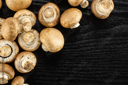 Fresh raw brown champignons table top on black wood background.