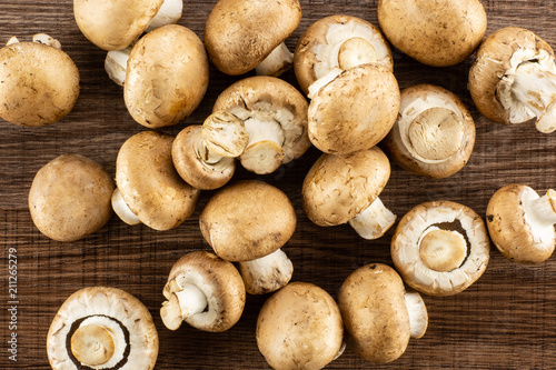 Fresh raw brown champignons flatlay on brown wood background.