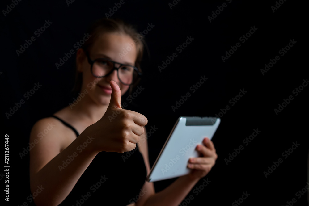 Girl teenager  playing a computer game on a dark background with copy space selective focus, concept of technology and video games