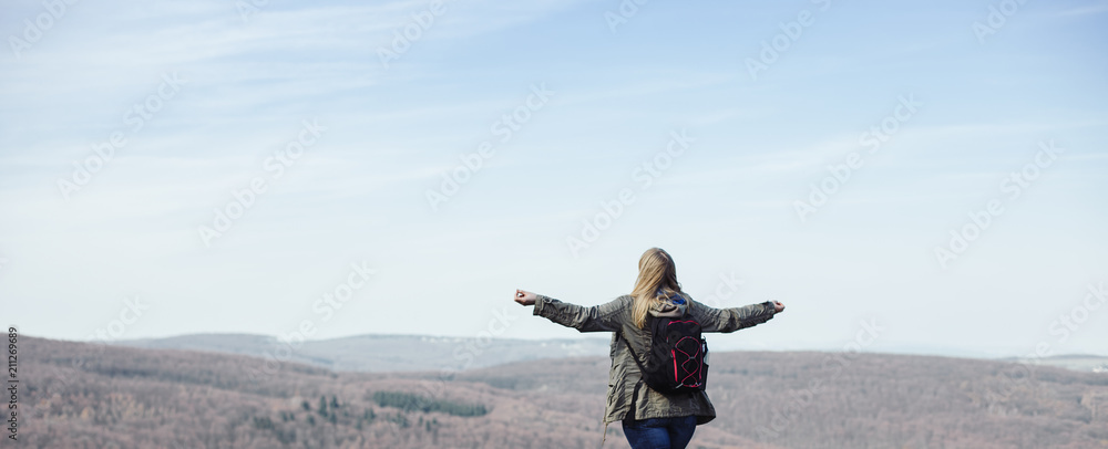 Woman hiking and standing on a hill with arms wide open Woman hiking and standing on a hill with arms wide open