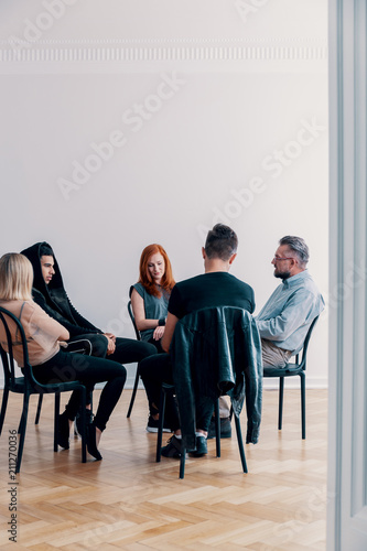Fototapeta Naklejka Na Ścianę i Meble -  Rebellious teenagers and psychologist sitting in a circle during group therapy