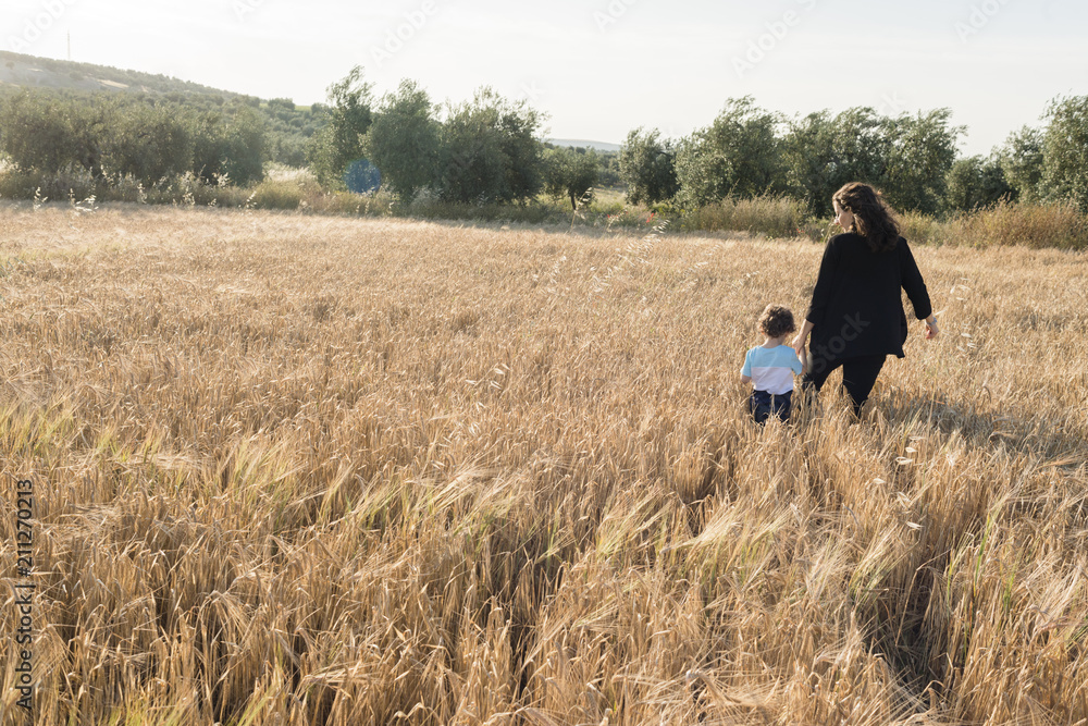 A woman and a child walking through a wheal field A woman and a child walking through a wheal field
