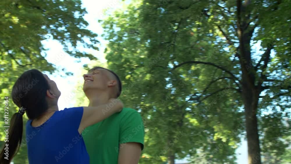 Portrait of carefree relaxed couple in love embrace enjoying leisure in summer park. Positive attractive couple hugging while resting together outdoors. Fly-by. Stabilized shot. Slow motion. Portrait of carefree relaxed couple in love embrace enjoying leisure in summer park. Positive attractive couple hugging while resting together outdoors. Fly-by. Stabilized shot. Slow motion.