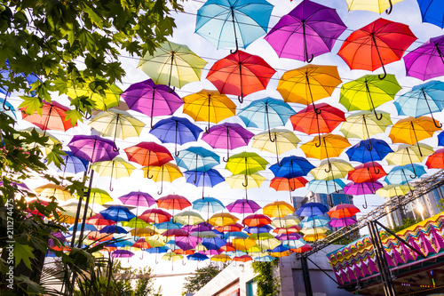 Colorful umbrellas background. Multi-colored umbrellas in the sky. Street decoration. © Alina