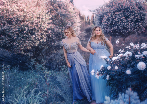 Family fairy photo shoot. Two blond women with wavy hair in luxurious, fabulous, blue dresses against the backdrop of flowering gardens. Artistic Photography