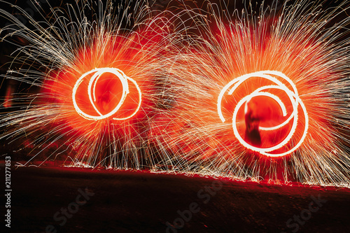 amazing fire show at night at festival or wedding party. Fire dancers swing, spinning red fire and man juggling with bright sparks in the night. fire show performance and entertainment