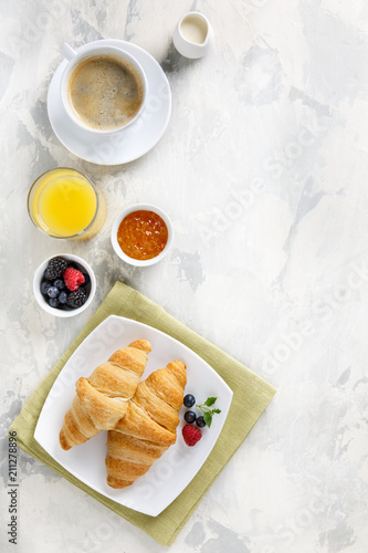 Breakfast served with croissants, coffee, orange juice and berries.