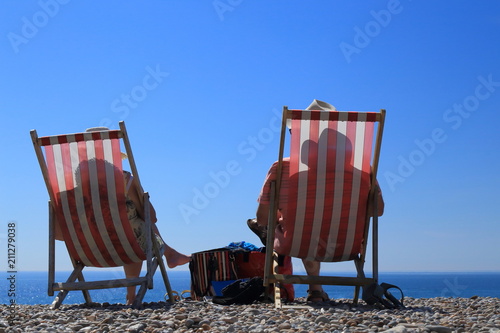 Shadows of people sitting on deck chairs on the beach in Devon