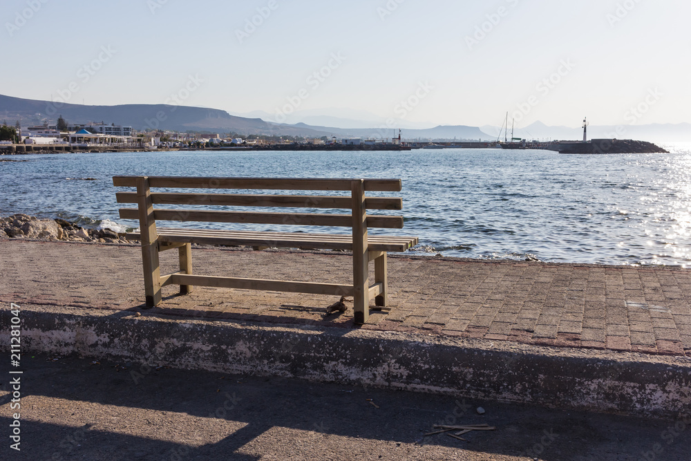 wooden bench on sunny at sea view, in front of beautiful with mountains and boats