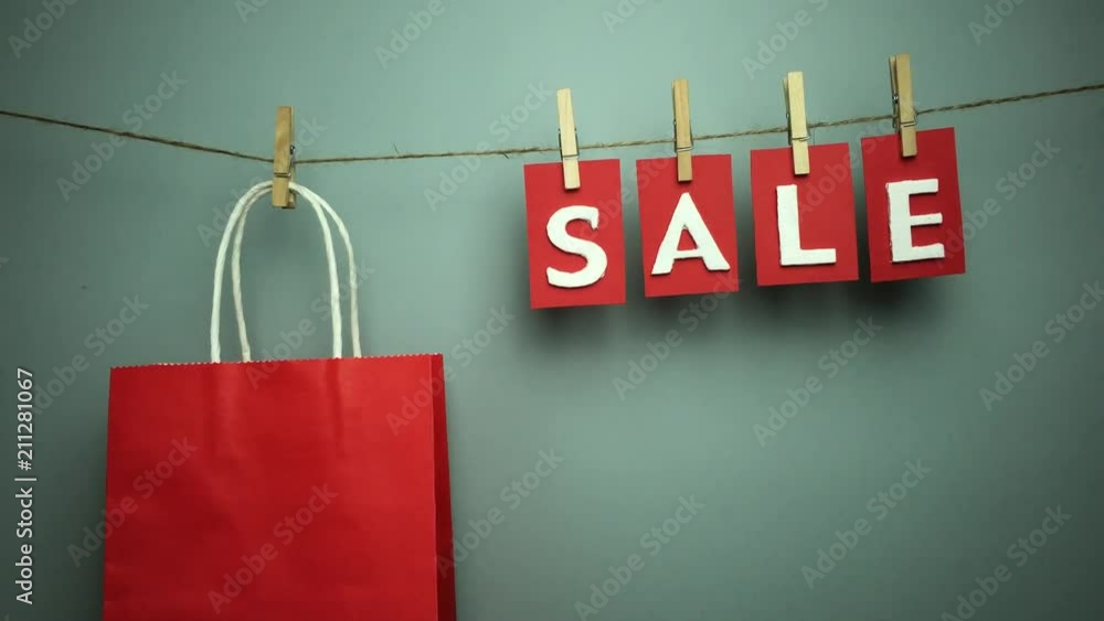 Palabra “sale” y bolsa de papel colgando de una cuerda con pinzas.