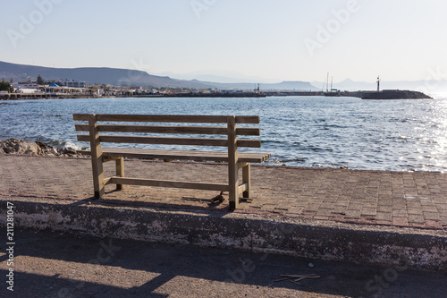wooden bench on sunny at sea view, in front of beautiful with mountains and boats © vladimircaribb