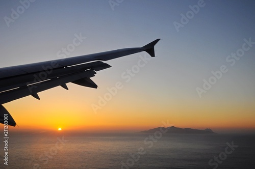 Viewing sunrise above sea on a flying plane toward Santorini Island in Greece
