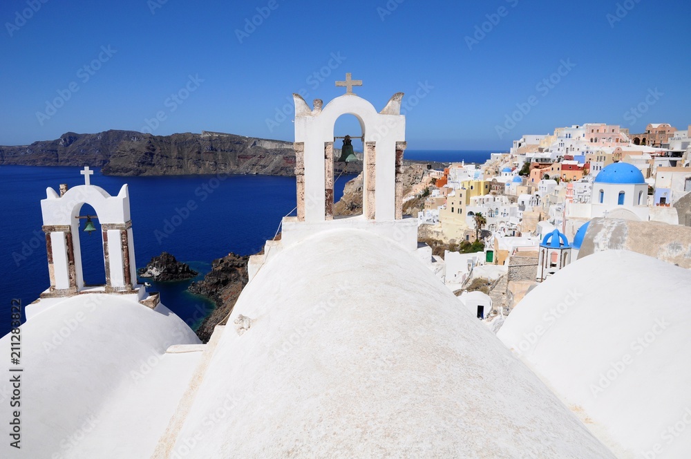 Famous stunning view of white architectures and church above the volcanic caldera in the village of Oia in Santorini island, Greece
