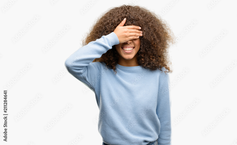 African american woman wearing a sweater smiling and laughing with hand on face covering eyes for surprise. Blind concept. African american woman wearing a sweater smiling and laughing with hand on face covering eyes for surprise. Blind concept.