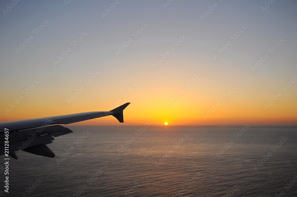 Viewing sunrise above sea on a flying plane toward Santorini Island in Greece