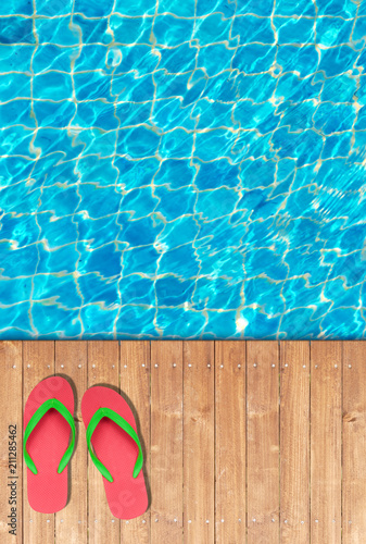 Wooden floor edge of swimming pool with red flip flops