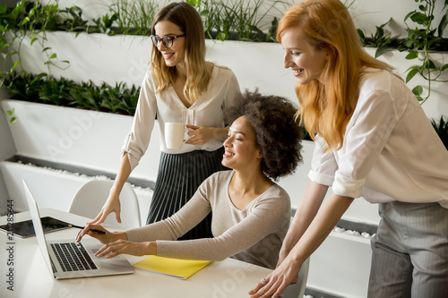 Cheerful professional multiracial women working in modern office
