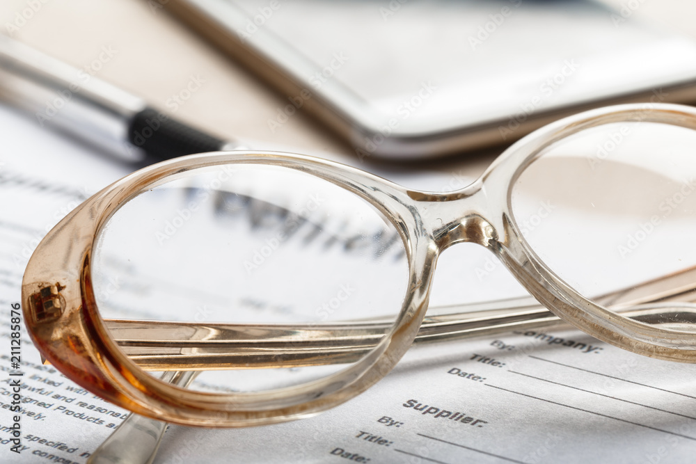Close up shot of Eyeglasses on document papers business concept Close up shot of Eyeglasses on document papers business concept
