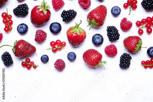 Bunch of mixed berries in harvest pile on white background. Colorful composition with fresh organic strawberry  blueberry  blackberry   redcurrant. Clean eating concept. Close up  copy space  top view