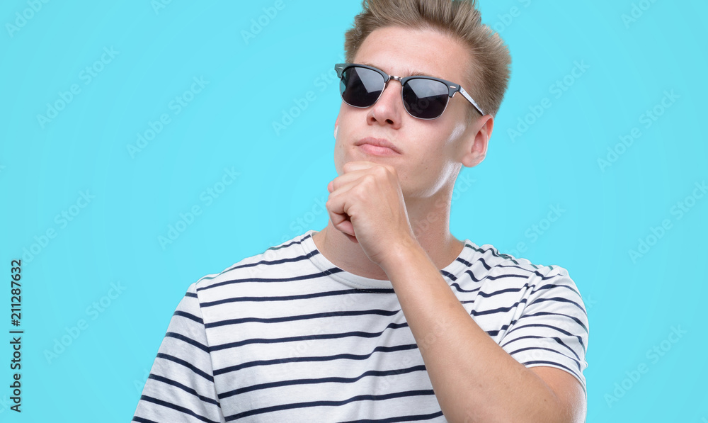 Fototapeta premium Young handsome blond man wearing sunglasess serious face thinking about question, very confused idea