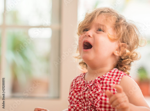 Photos Beautiful blond child crying and shouting with tantrum at home.