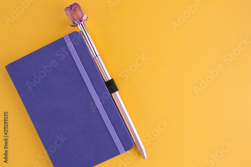 Purple notebook with pen on a yellow background