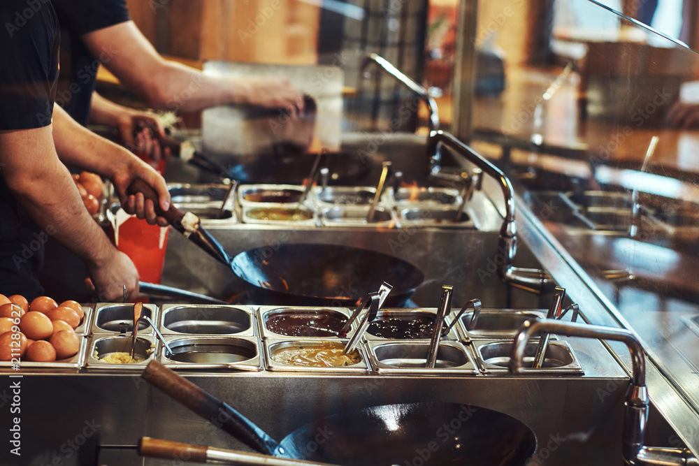 Cooking process in an Asian restaurant. Cook is stirring vegetables in wok. Cooking process in an Asian restaurant. Cook is stirring vegetables in wok.