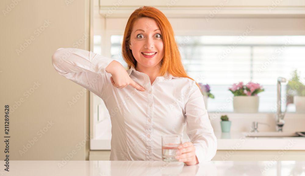Thirsty redhead woman and glass of water with surprise face pointing finger to himself Thirsty redhead woman and glass of water with surprise face pointing finger to himself