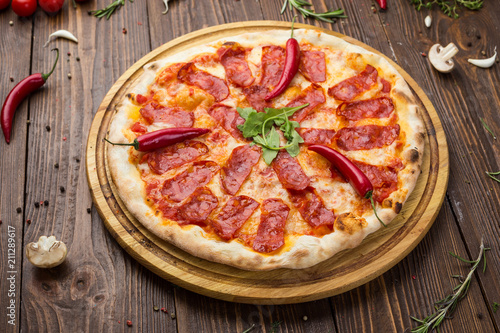 Pizza pepperoni with mozzarella cheese, salami and arugula on wooden background