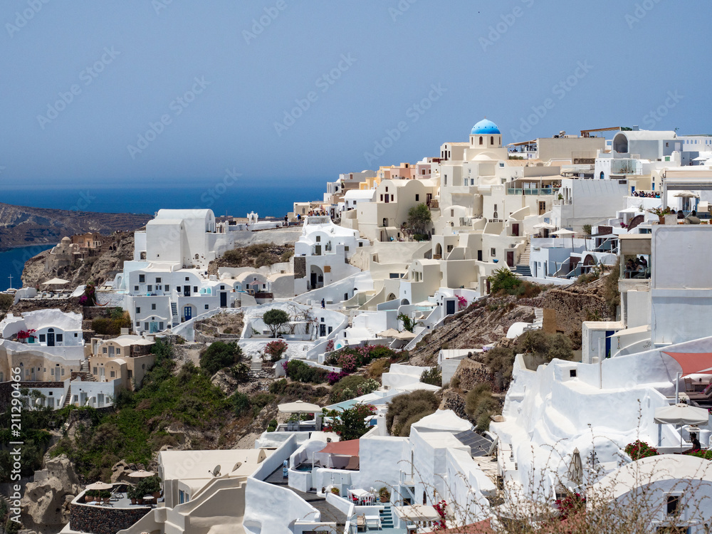 Beautiful Oia town, Santorini island, Greece: Panoramic view. Traditional and famous white houses and churches with blue domes over the Caldera, Aegean sea.
