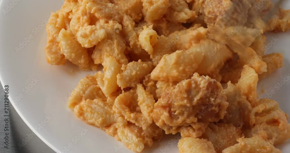 Close video of spicy chicken nuggets with macaroni and cheese on a white plate being stirred then eaten with a fork. Close video of spicy chicken nuggets with macaroni and cheese on a white plate being stirred then eaten with a fork.