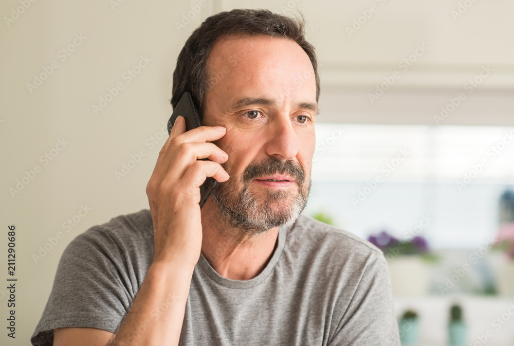 Middle age man using smartphone with a confident expression on smart face thinking serious Middle age man using smartphone with a confident expression on smart face thinking serious