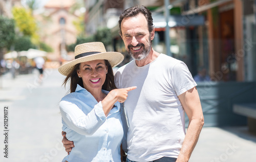 Middle age couple down the street very happy pointing with hand and finger