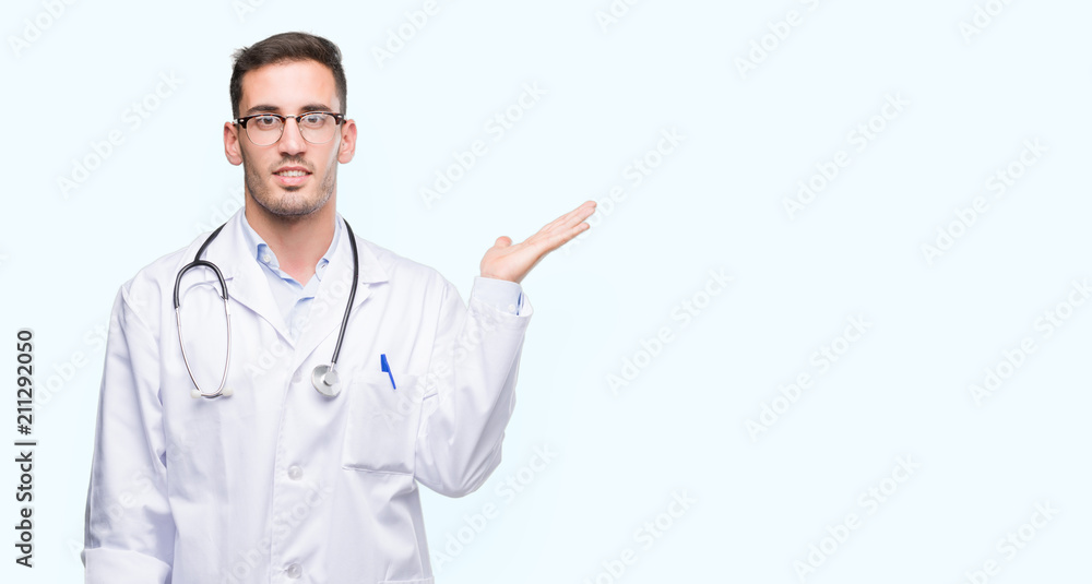Handsome young doctor man smiling cheerful presenting and pointing with palm of hand looking at the camera. Handsome young doctor man smiling cheerful presenting and pointing with palm of hand looking at the camera.