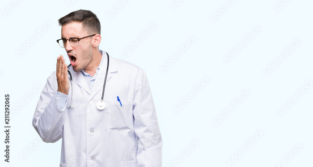 Handsome young doctor man bored yawning tired covering mouth with hand. Restless and sleepiness. Handsome young doctor man bored yawning tired covering mouth with hand. Restless and sleepiness.
