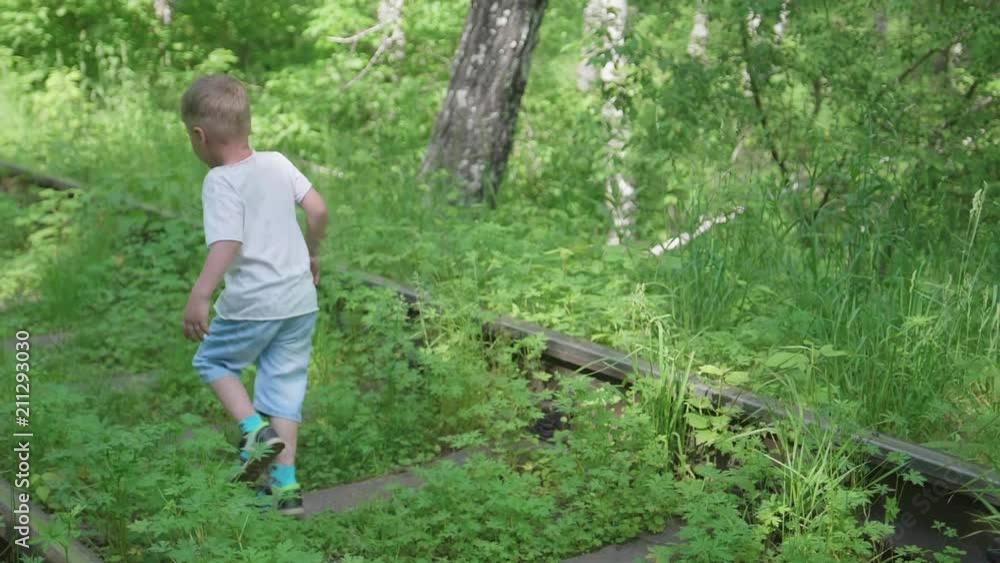 Lonely boy running around on the railroad tracks. Dangerous games and entertainment Lonely boy running around on the railroad tracks. Dangerous games and entertainment