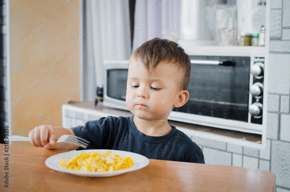 the child greedily in the kitchen eating an omelet in the afternoon in the summer the child greedily in the kitchen eating an omelet in the afternoon in the summer