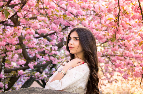 portrait of a young teenage girl looking at blooming sakura trees