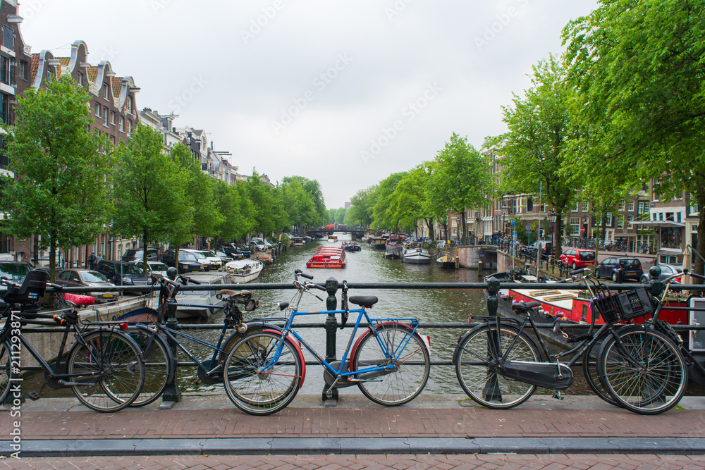 Amsterdam, Netherlands - May 201: Beautiful summer sunrise on the famous UNESCO world heritage canals of Amsterdam, The Netherlands, with vibrant flowers and bicycles on a bridge.
