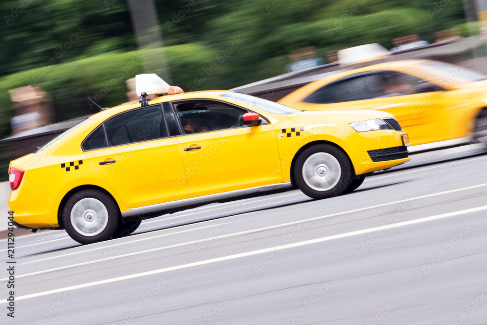 yellow taxi rides with great speed on the road, the effect of blur in the traffic
