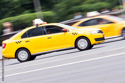 yellow taxi rides with great speed on the road, the effect of blur in the traffic