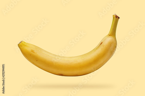 Single fresh, yellow, ripe banana over yellow background photo